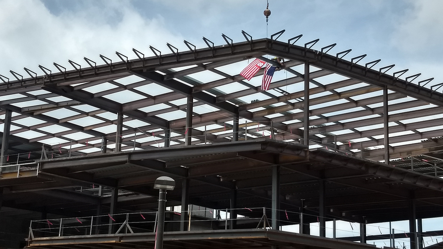 Workers attach a steel beam to the structure of the new Wellness and Recreation Center.