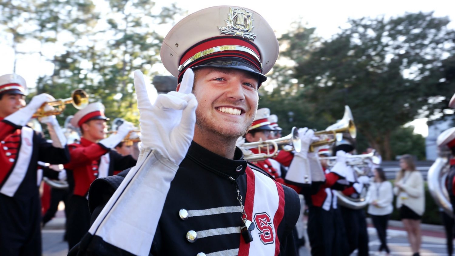 Thomas Peters smiles and does the wolfie in his band uniform