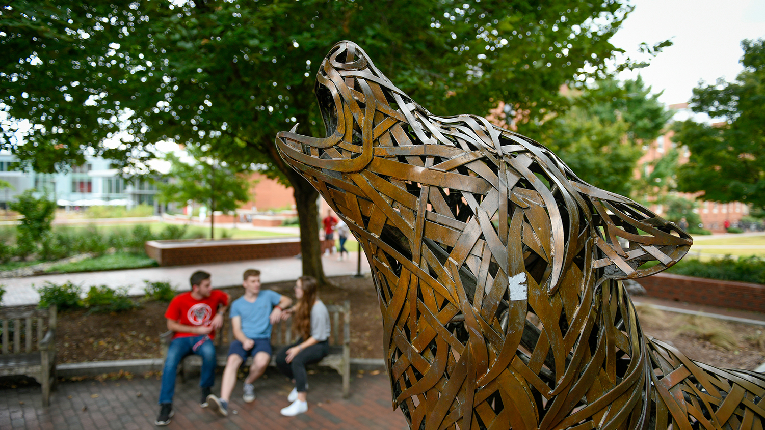 A bronze wolf howls in Wolf Plaza on NC State's campus.