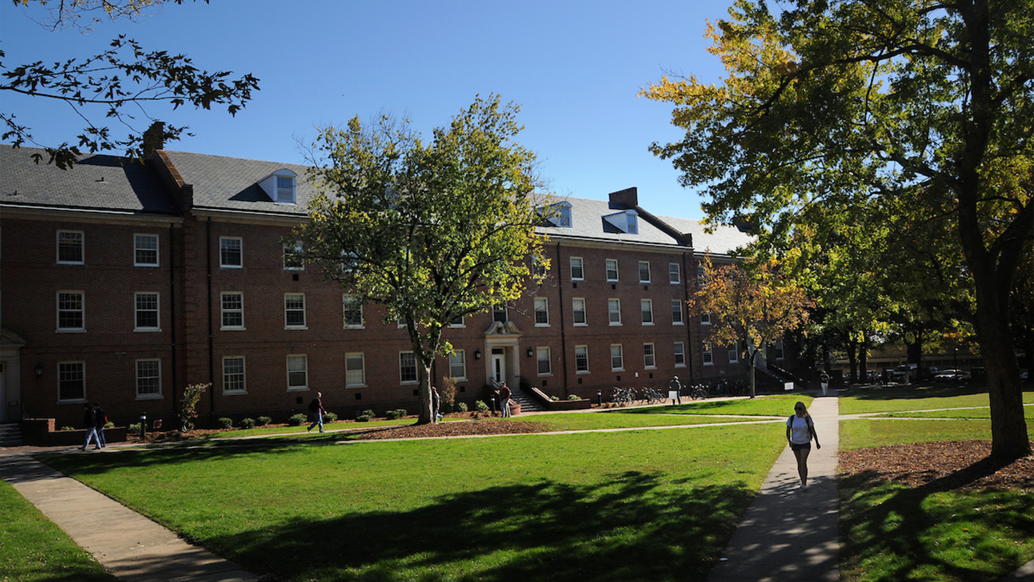 Fall leaves and students walking in front of Alexander residence hall