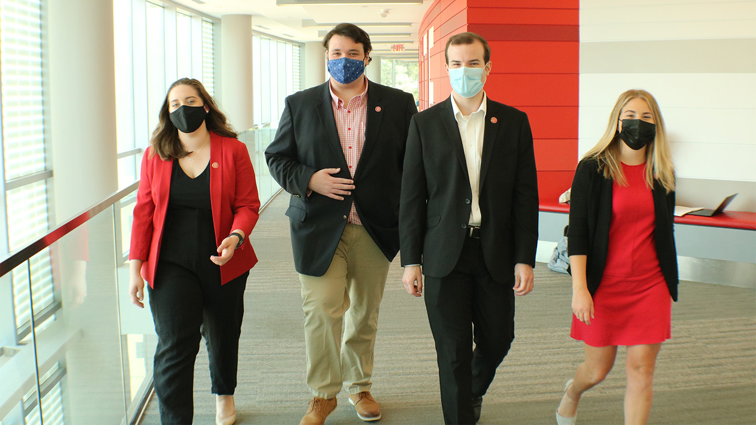 Four Student Government leaders walk side by side through a hallway in Talley Student Union