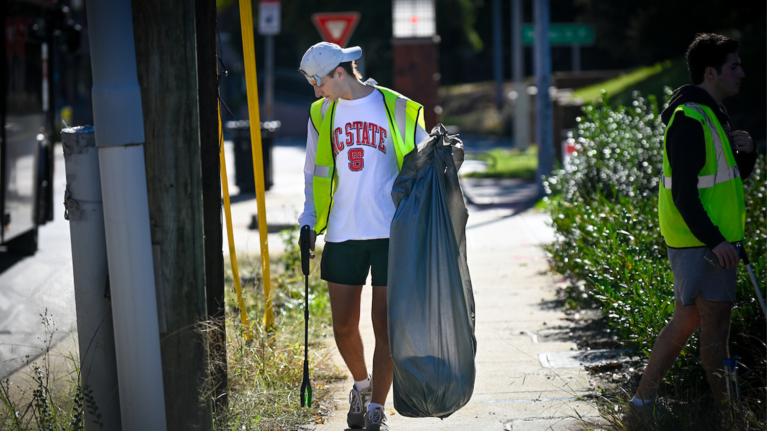 A student picks up trash along Hillsborough Street