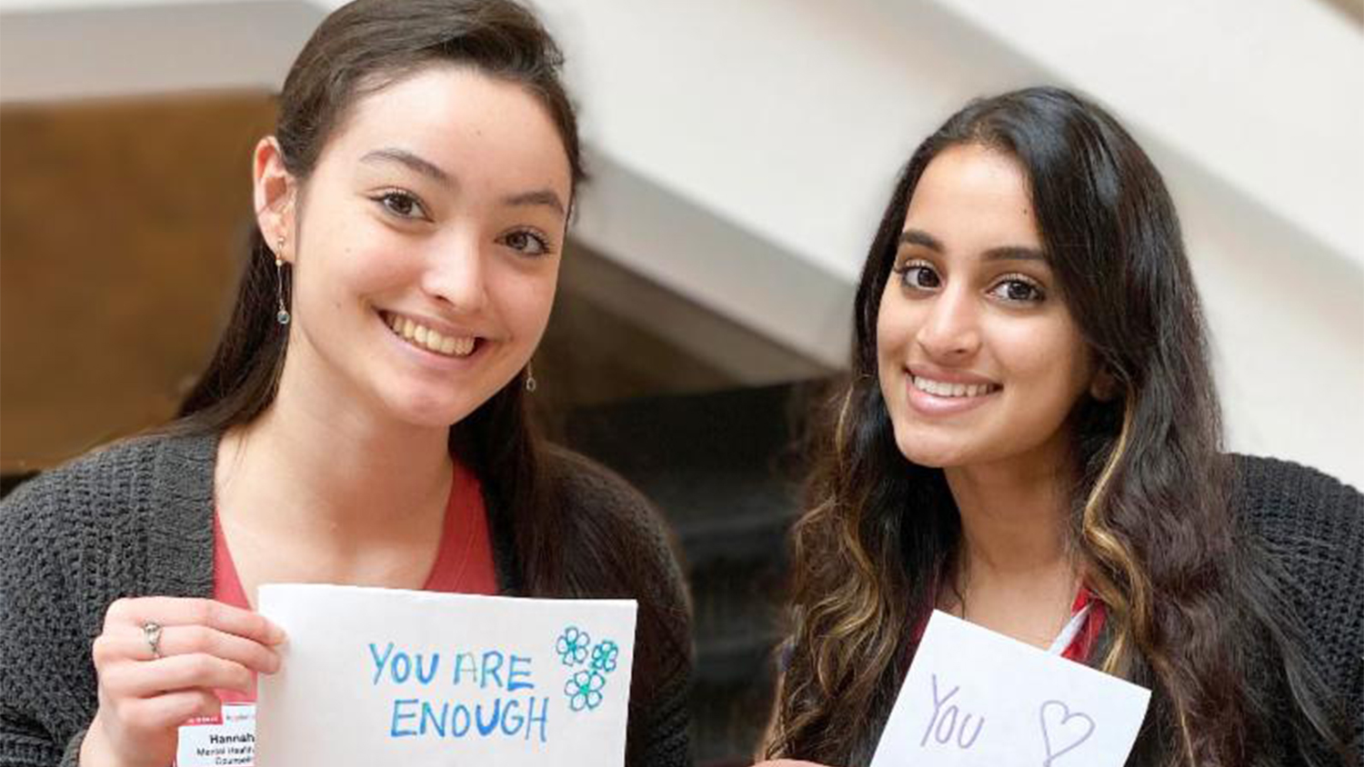 Two students hold signs with messages of encouragement