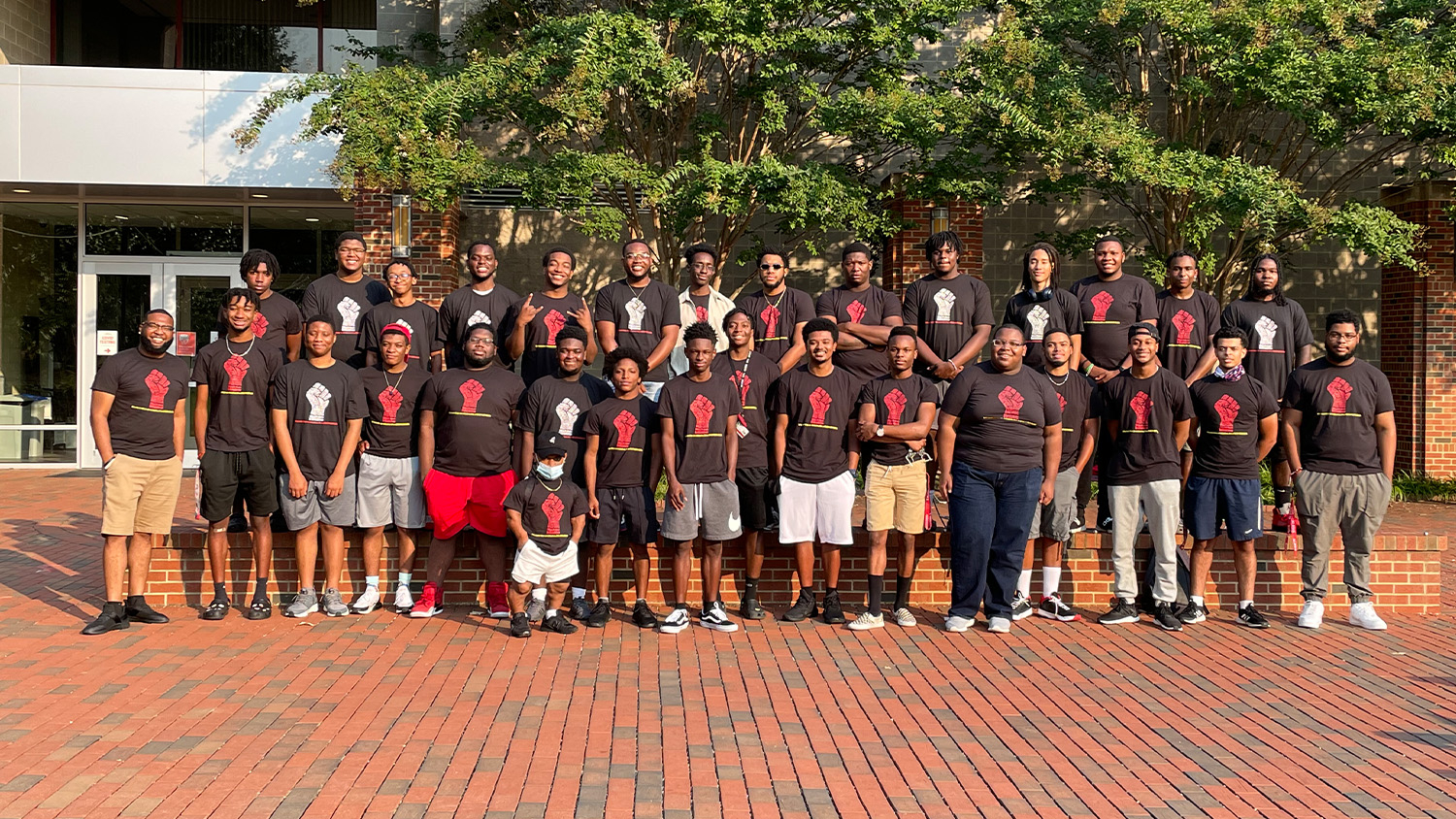 A group of students wearing black T-shirts with a red fist on them for the Black Male Initiative