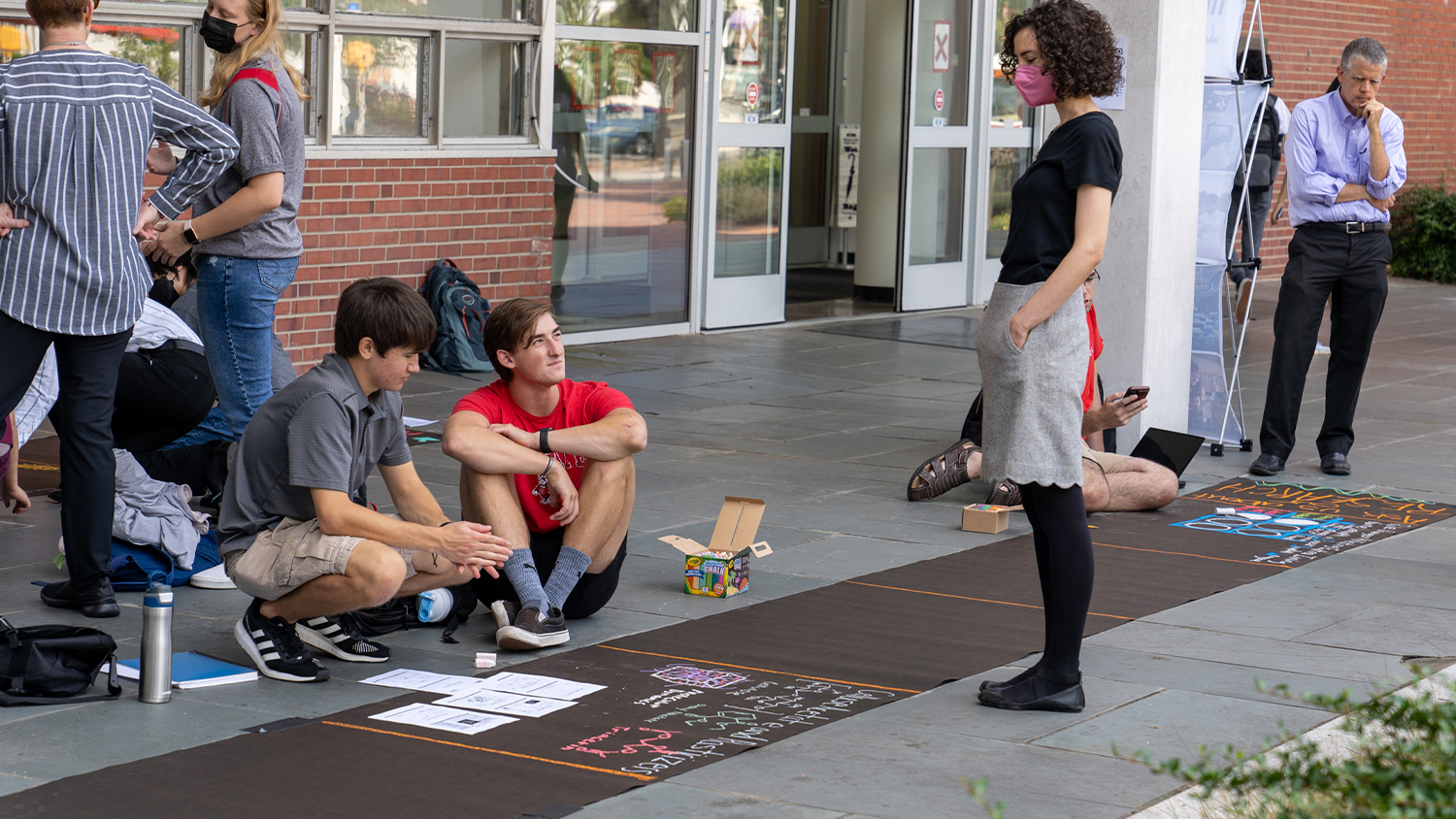 Catherine Showalter talks to students drawing in chalk at the Sidewalk Symposium last fall