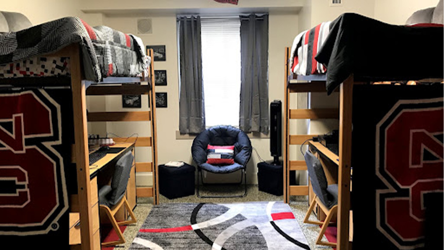 The interior of a residence hall room, with two bunk beds and NC State blankets on the end of them