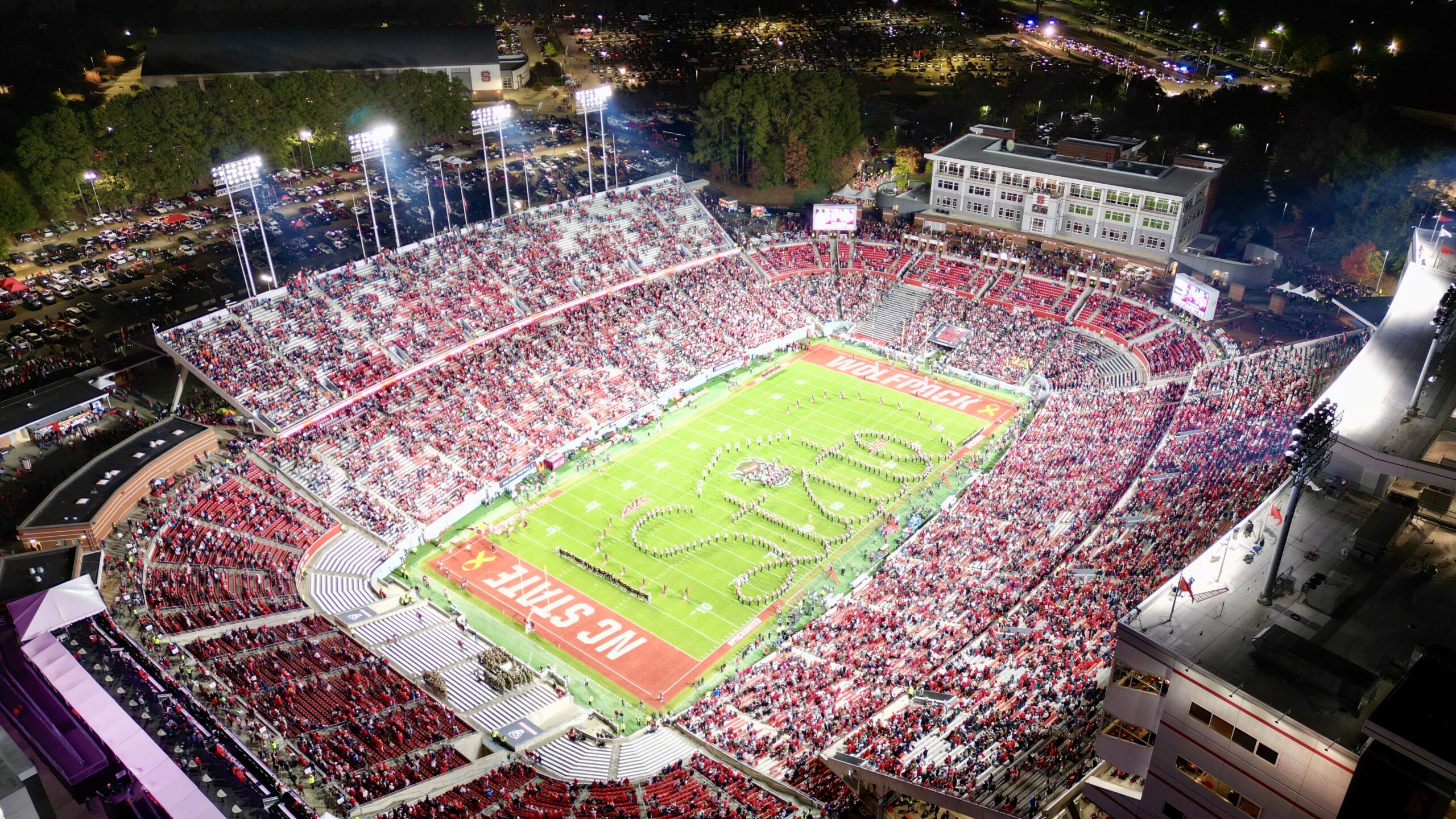 An aerial photo of Carter-Finley Stadium during the marching band's halftime show, where the band spells out "state"
