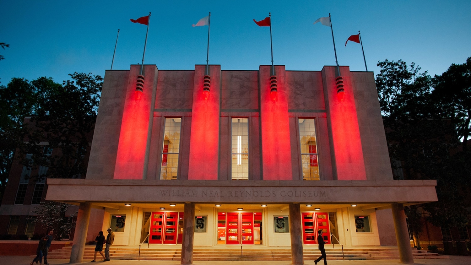 The outside of Reynolds Coliseum lit up at night