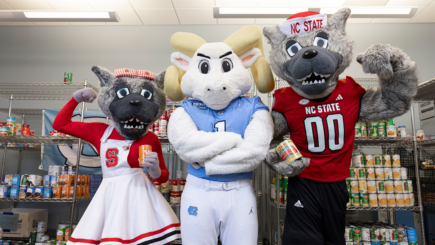 NC State and UNC's mascots gather in front of shelves of canned food.